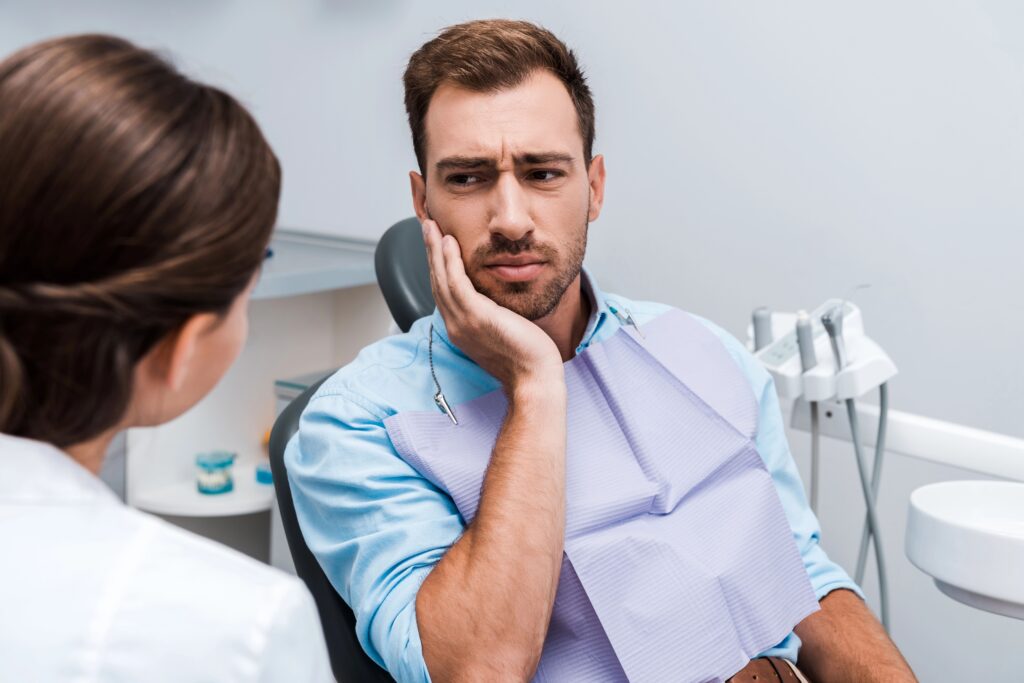 Mężczyzna z bolącym zębem na fotelu dentystycznym