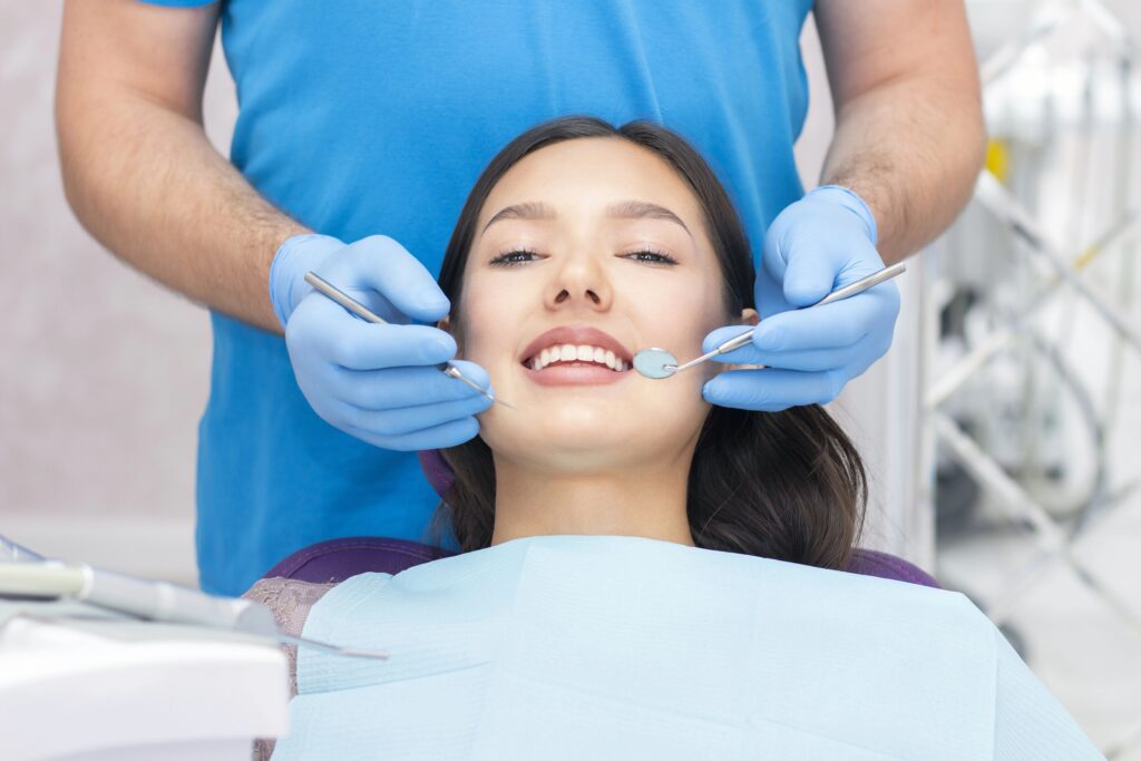 Kobieta siedzi na fotelu dentystycznym i poddaje swoje uzębienie kontroli